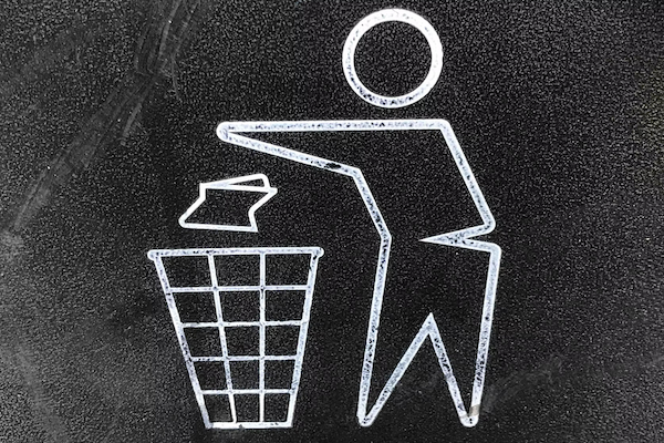 chalk drawing of a person throwing waste in to a trash bin